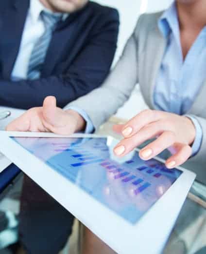 A business woman on an iPad showing data charts to a business man.